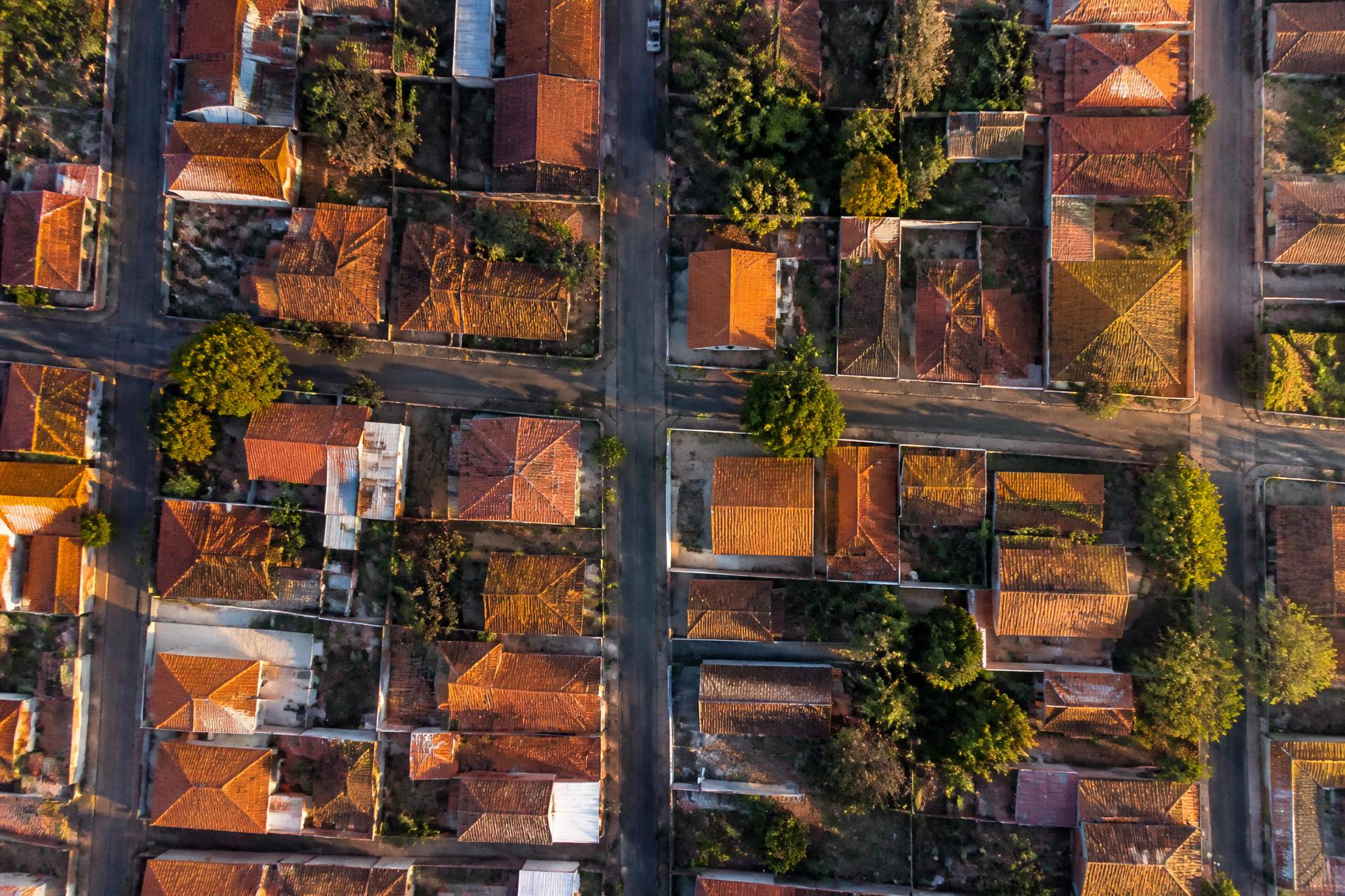 Vista aérea de um bairro residencial com telhados de telha cerâmica ao fim da tarde